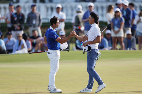 Min Woo Lee shakes hands with Viktor Hovland on the 18th green.