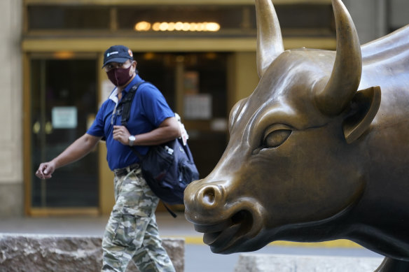 A man wearing a mask passes the charging bull statue in Manhattan.