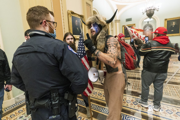 Jacob Chansley, pictured in face paint and  wearing a fur hat with horns during the riot, has been charged by police.