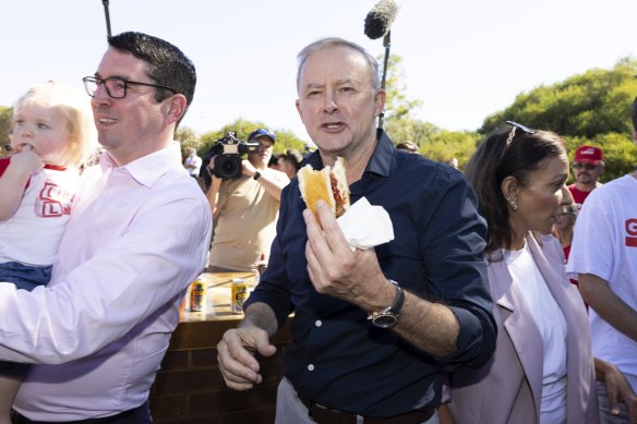 Anthony Albanese grabs a sausage  sandwich during a campaign visit to Perth last month.