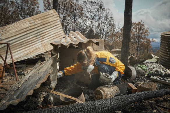 Volunteer firefighter Anika Craney searches through the remains of her home near Cobargo.
