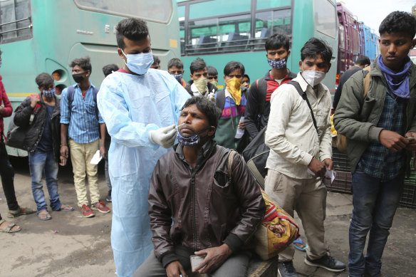 A health worker tests a man for COVID-19 at a bus station in Jammu, India, last month.