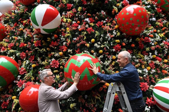 Stephen Gilby, event producer at City of Sydney, and Tim Clarkson, the chief executive of Chas Clarkson, apply final touches to the Martin Place tree.