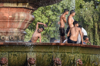 People play with water in a fountain on a hot summer afternoon at India Gate in New Delhi.