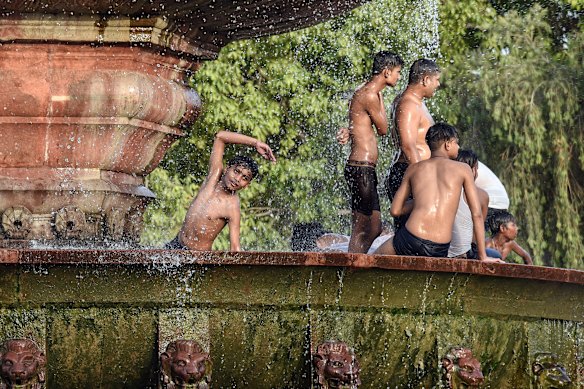 People play with water in a fountain on a hot summer afternoon at India Gate in New Delhi.