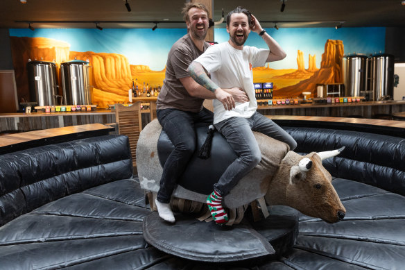 I proprietari Josh Oljans (a sinistra) e Karl Van Buren cavalcano il toro meccanico al Moon Dog Brewery a Footscray. 