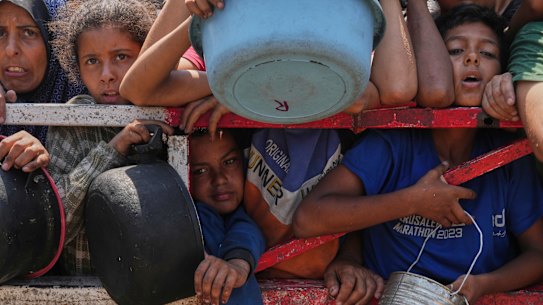 Palestinians struggle to get donated food at a community kitchen, in Gaza City, northern Gaza Strip, on Saturday, July 26.