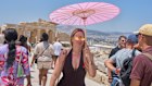 Woman hold parisol while walking in front of the Acropolis