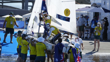 Mathew Belcher and Will Ryan have their boat carried on shore after winning the men’s 470 gold medal.
