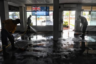 RFS workers sweep out water from the floods at the Camden RSL on Friday.