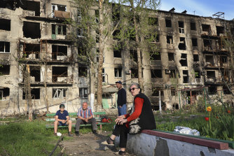Residents sit in the yard of their damaged building in Mariupol.