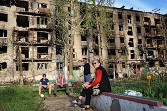 Residents sit in the yard of their damaged building in Mariupol.