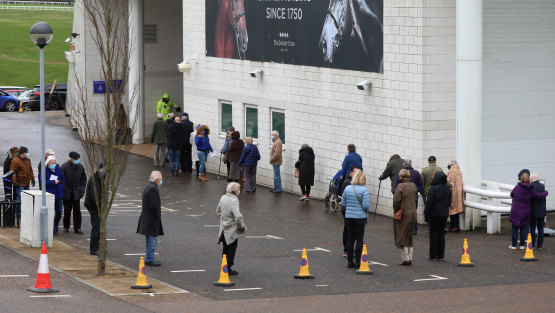 Members of the public queue to receive the Oxford-AstraZeneca coronavirus vaccine at a mass vaccination centre at a Epsom racecourse in England.