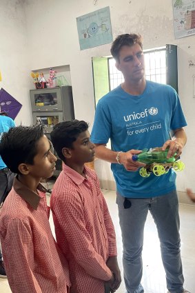 Australian cricket captain Pat Cummins with two students at a school in Lucknow.