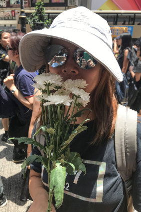 Janet, 30, carries white flowers at Sunday's Hong Kong march in recognition of the protester who earlier fell to his death.  