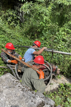 Men from a nearby village take a repaired pump back into one of the caves in the Tenglong complex.