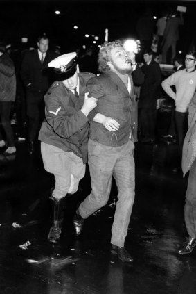 A bloodied protester is led away by the police