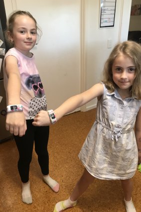 Mackenna (left) and Piper sporting their activity watches which tracks the coins they've earned.