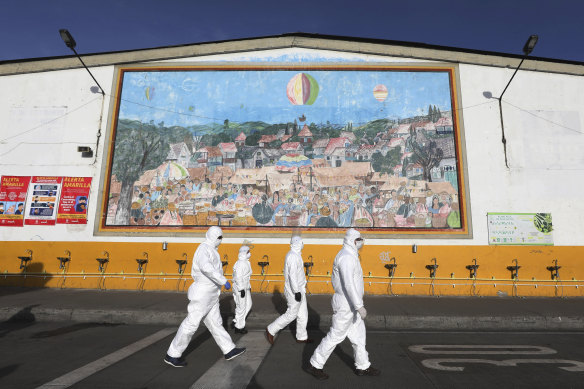 Workers in protective suits walk past sinks for hand washing at the Corabastos in Bogota, one of Latin America's largest food distribution centres.