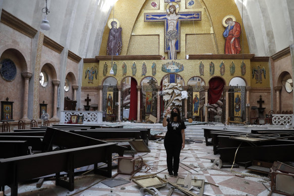 A woman takes pictures by her mobile phone for a damaged church.