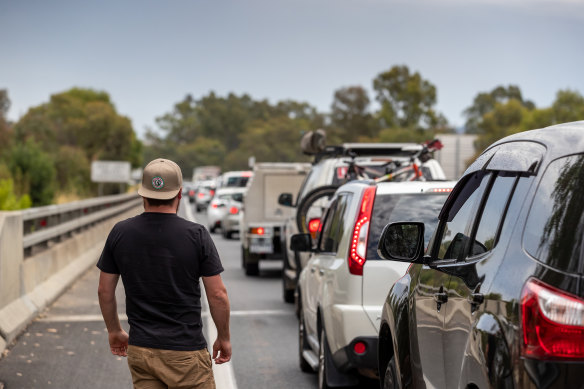 Nathan Goring looks on as a long queue of vehicles forms at the Victorian border near Albury.