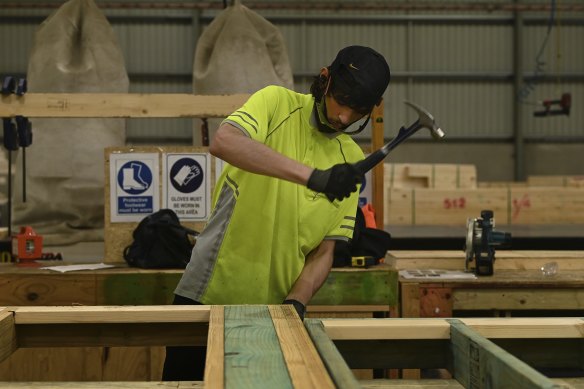 Workers in the factory assemble roof trusses and wall frames.