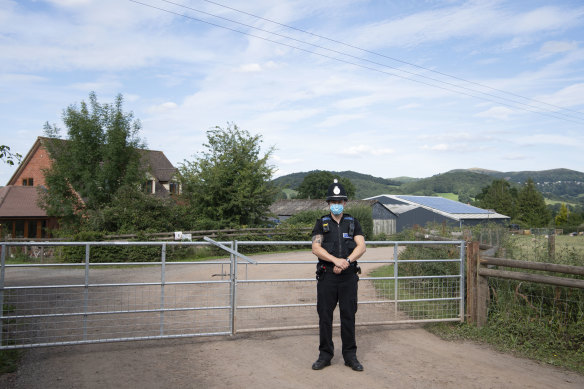 A police officer guards a farm in England where a COVID-19 cluster has occurred.