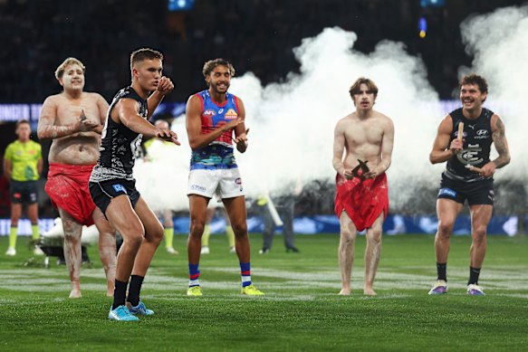 Debutant Jack Ison participates in a pre-match Indigenous dance alongside Arthur Jones and Zac Williams.