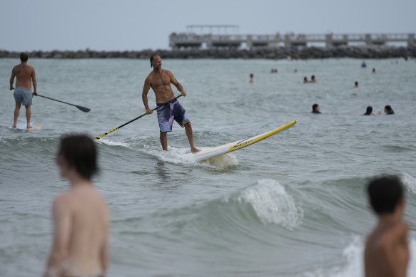 Graziano La Grasta, a local contractor and paddleboard enthusiast, rides a small wave in South Beach, Miami Beach, Florida, on Friday.