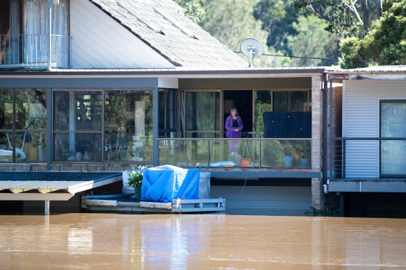 A woman watches the water from the top floor of her flood inundated house in Lower MacDonald.
