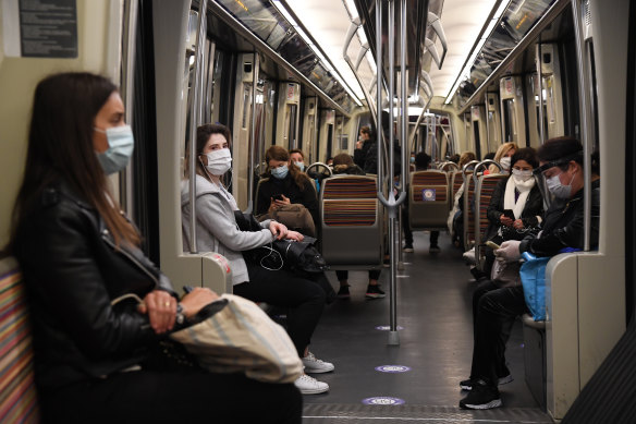 Commuters in protective masks practise social distancing on a train in Paris on Monday.