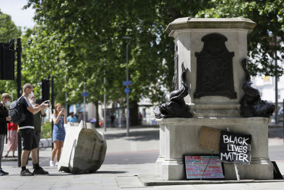 People look at the pedestal of the toppled statue of Edward Colston.