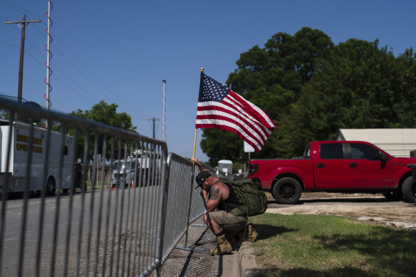 Jarrod Tomassi, 45, holds an American flag outside Robb Elementary School while praying for the victims killed in this week’s school shooting in Uvalde, Texas.