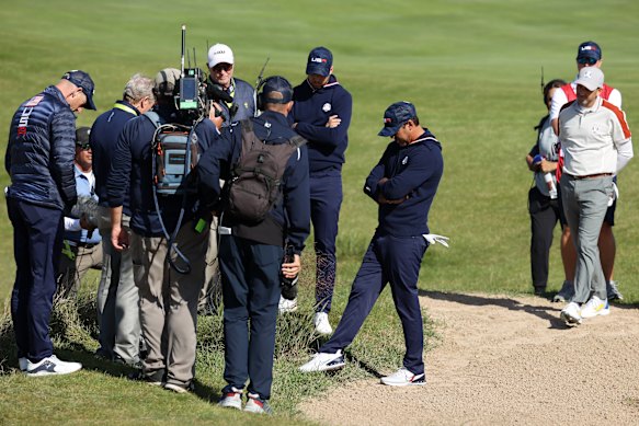 A rules lawyer inspects the lie of a ball for Daniel Berger of team United States and Brooks Koepka of team United States on the 15th hole.