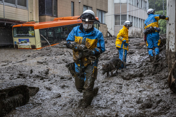 A police officer with a search and rescue dog, searches the area around the site of a landslide on July 04, 2021 in Atami, Shizuoka, Japan. 