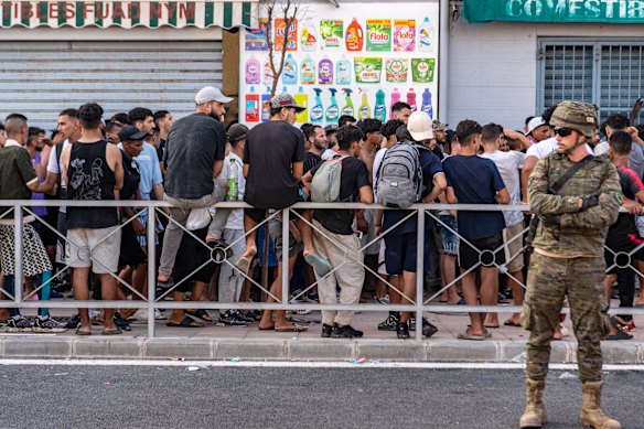 Migrants wait for a shop to open so they can buy food after crossing from Morocco into the Spanish exclave of Ceuta.