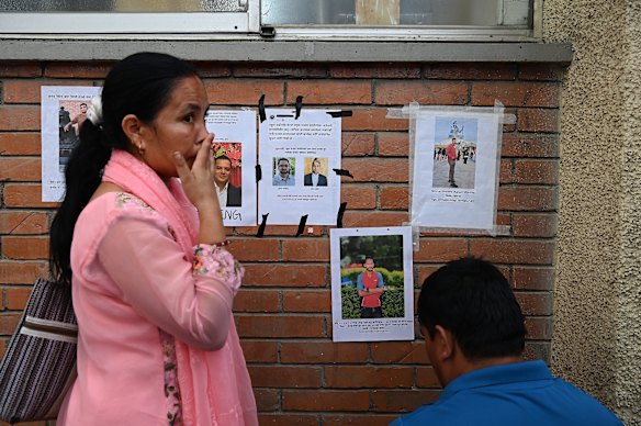 At the Tribhuvan University Teaching Hospital, Kabita Khadka (left) and a family member put up a poster of their relative Bhupendra Khadka who is missing.