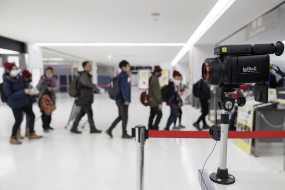 Passengers walk past a thermal scanner upon their arrival at Narita airport in Japan. 