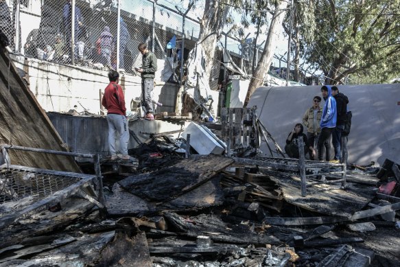 Migrants stand on a burnt container home in Moria refugee camp on Lesbos, Greece.