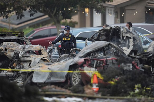 Authorities comb the wreckage and burned out vehicles close to the crash site.