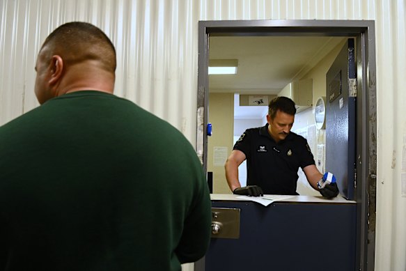 Correctional officer Josh Watson hands a urine sample jar to a participant as part of a mandatory testing regime. 