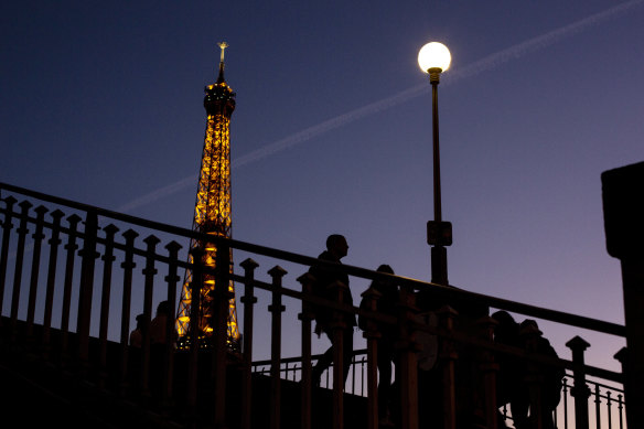 Lights out: People walk on a bridge next to the Eiffel Tower in Paris.