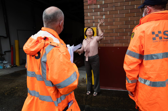 SES members talk to business owner Jenny Lu from Victory Smash and Mechanical Repairs in Marrickville about the need to protect her property from more flooding.