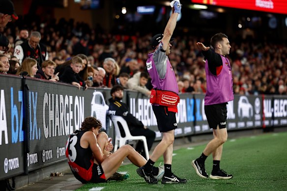 Harrison Jones clutches his injured leg on the boundary line.