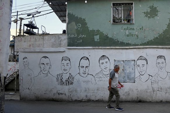 A man walks past paintings of those regarded as martyrs on a wall in Dheisheh refugee camp in Bethhlehem, West Bank.