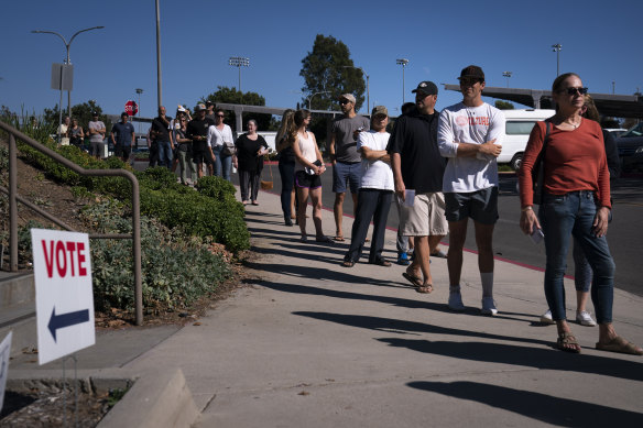 People wait in line outside a vote centre to cast their ballots in Huntington Beach, California, on Tuesday.
