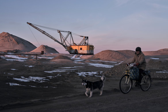 A woman cycles past with her dog as bucket-wheel excavators mine rare earth materials in the Zhytomyr region of Ukraine on Wednesday.