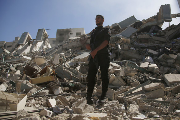 A policeman stands on rubble from a building housing AP office and other media in Gaza City that was destroyed after Israeli warplanes demolished it, Saturday, May 15, 2021.  The airstrike Saturday came roughly an hour after the Israeli military ordered people to evacuate the building. 