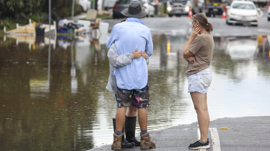 BRISBANE, AUSTRALIA - MARCH 03: People hug while watching the floodwaters at Eagle Tce, Auchenflower on March 03, 2022 in Brisbane, Australia. From Brisbane in Queensland to Lismore in northern New South Wales, flood-affected communities are cleaning up debris as the weather system moves south towards Sydney. (Photo by Peter Wallis/Getty Images)