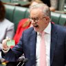 Prime Minister Anthony Albanese holds up a medicare card during Question Time.